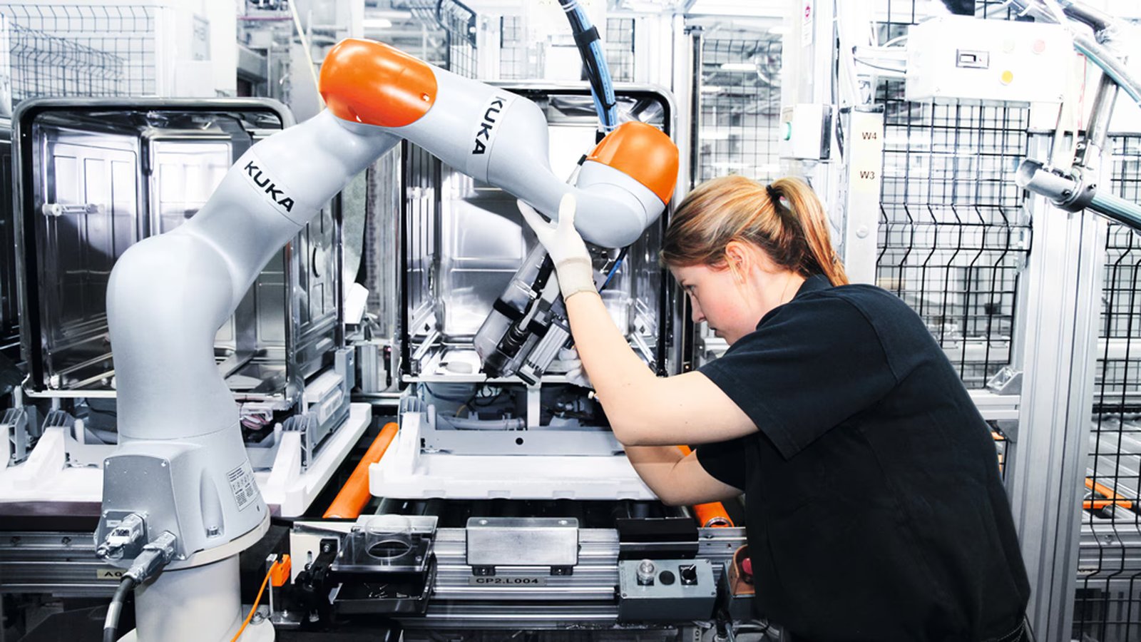 A technician adjusts a collaborative robotic arm on an automated manufacturing line