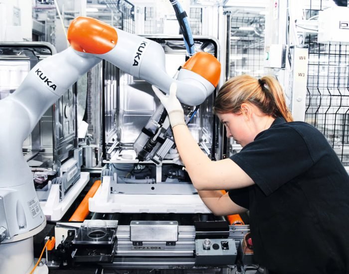 A technician adjusts a collaborative robotic arm on an automated manufacturing line